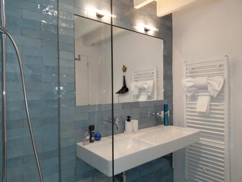 une salle de bain avec un lavabo et une douche en verre dans l'établissement Logies De Lelie - Antwerpen Zuid, à Anvers