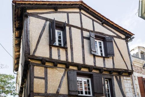 una casa vieja con ventanas con contraventanas negras en Le Sous-Bois, une parenthèse nature, en Bergerac