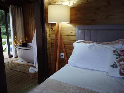 ein Schlafzimmer mit einem Bett mit einer Lampe und einem Fenster in der Unterkunft Morro do Eurico - Descanso e privacidade in Praia Grande