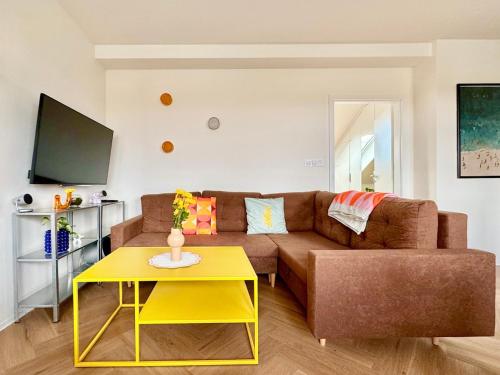 a living room with a brown couch and a yellow table at New flat close to center in Komárov
