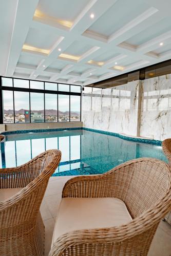 a swimming pool with two wicker chairs and a table at Hotel Don Ruben Business And Suites Juventud Chihuahua in Chihuahua