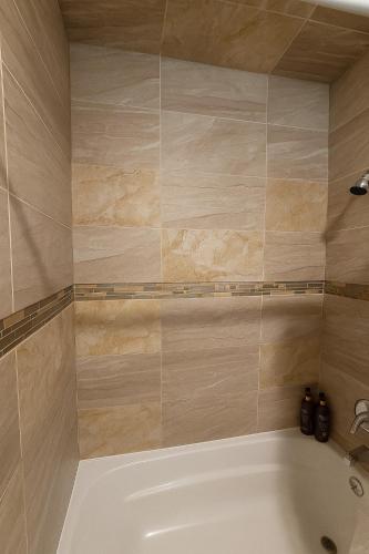 a bathroom with a white tub and a tile wall at Downtown Cheyenne in Cheyenne