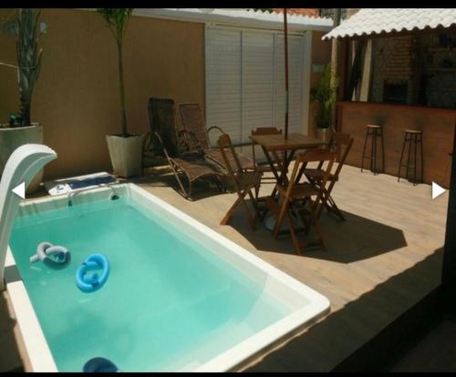 ein Swimmingpool in einem Hinterhof mit einem Tisch und Stühlen in der Unterkunft Casa top pertinho da praia com piscina e área gourmet in Arraial do Cabo