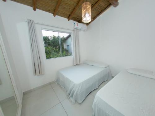 a white room with two beds and a window at Recanto do Villa 3 in Trancoso
