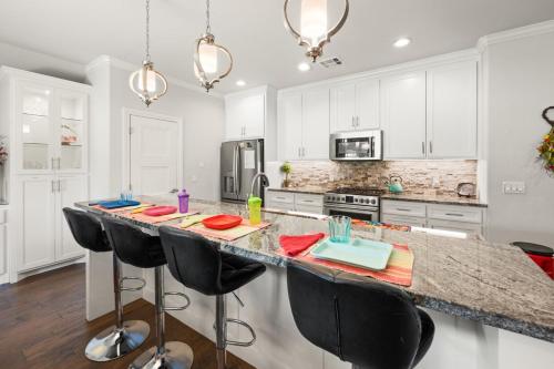 eine Küche mit weißen Schränken und einer großen Insel mit schwarzen Barhockern in der Unterkunft Chic 4BR Retreat Near Downtown in Oklahoma City