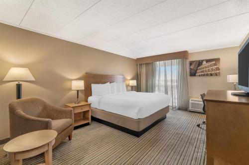 a hotel room with a bed and a chair at Best Western Plus Waltham Boston in Waltham