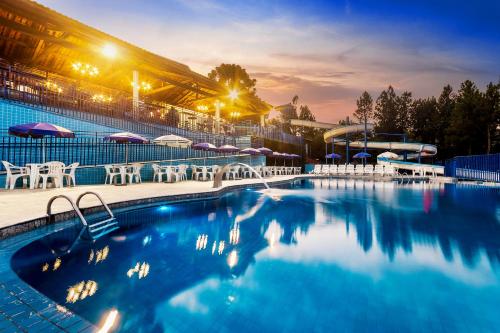 a swimming pool with chairs and umbrellas at night at Hotel Vilage Inn All Inclusive Poços de Caldas By Nacional Inn in Poços de Caldas