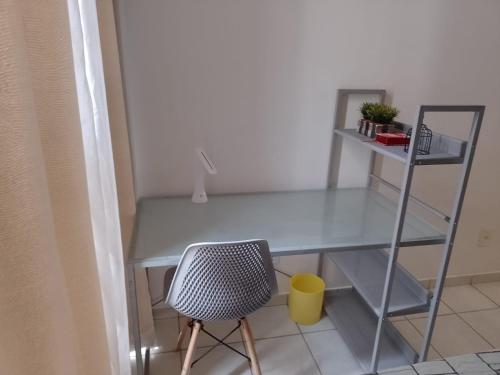 a glass desk with a chair and a shelf at Lugar encantado - Apartamento in Brasilia