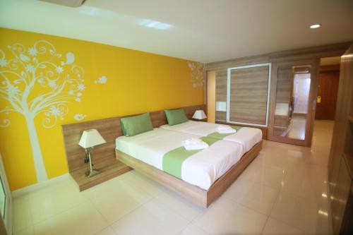 a bedroom with a large bed with a yellow wall at Pintree Pattaya in Pattaya South