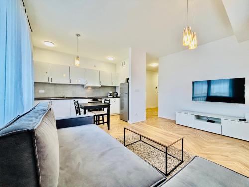 a living room with a couch and a kitchen at Apartamenty przy Szpitalu na Bema in Lubin