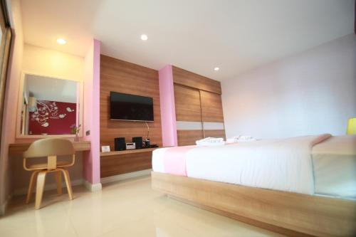 a bedroom with a bed and a desk and a tv at Pintree Pattaya in Pattaya South