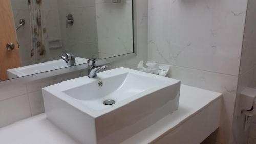a white bathroom with a sink and a mirror at Ariston Hotel Bangkok in Bangkok