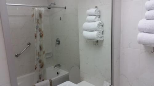 a bathroom with a shower and a toilet and towels at Ariston Hotel Bangkok in Bangkok