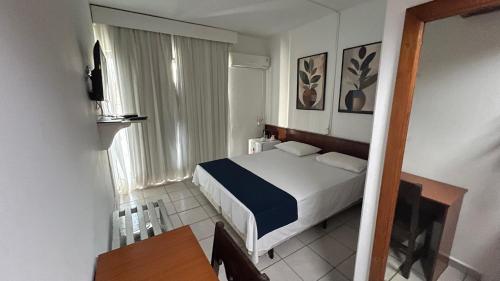 a small bedroom with a bed and a window at Hotel Dourado in Alfenas