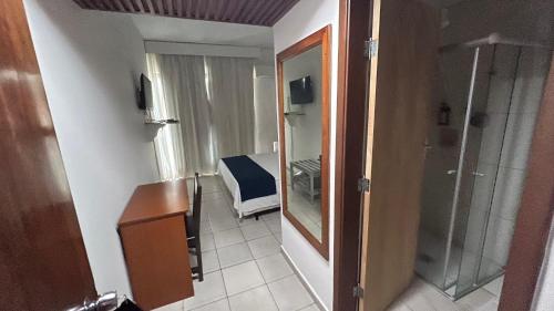 a room with a desk and a mirror and a room at Hotel Dourado in Alfenas