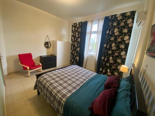 a bedroom with a bed and a red chair at Nefele - Athens Airport Home in Artemida