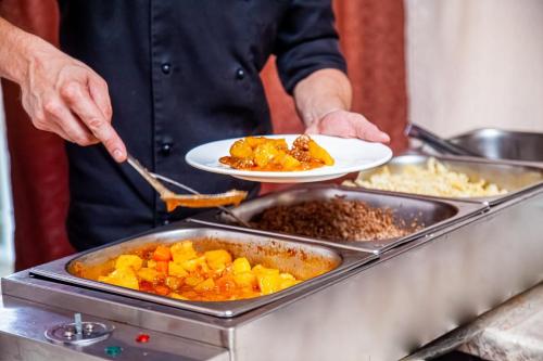 a man holding two plates of food in a kitchen at Turgen Resort in Taūtürgen