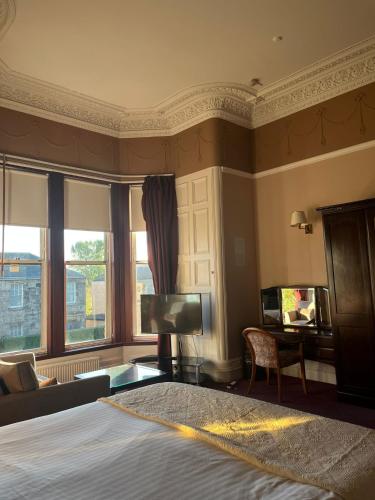 a bedroom with a bed and a couch and a television at Edinburgh Whisky House Hotel in Edinburgh