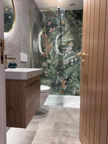 La salle de bains est pourvue de toilettes et d'une fresque murale représentant des plantes. dans l'établissement Luxury 2Bed 2 Bath Apartment in Historic Bank, à Leyburn