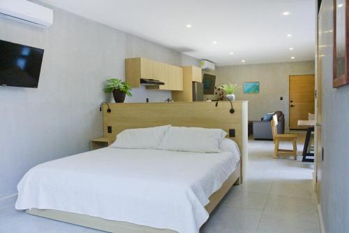 ein Schlafzimmer mit einem weißen Bett und ein Wohnzimmer in der Unterkunft TerraCondos Loft 203 & 204 in Bahías de Huatulco