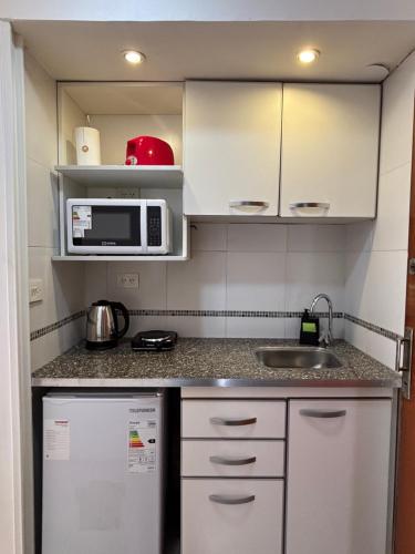 a small kitchen with a sink and a microwave at Minisuite Estación Ramos Mejía in Ramos Mejía
