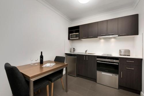 a kitchen with a wooden table and a table and chairs at Quest Dandenong in Dandenong