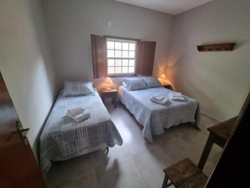 チラデンテスにあるPouso dos Arcanjosのベッド2台と窓のある寝室
