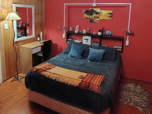 Un dormitorio con una cama grande con una pared roja. en 100 años ciprés, en Río Gallegos