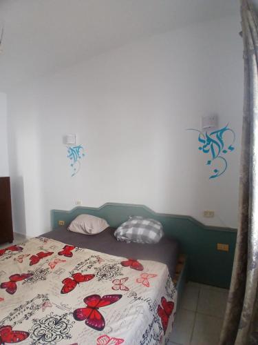 ein Schlafzimmer mit einem Bett mit roten Blumen darauf in der Unterkunft Appartement Nicolas Djerba route du phare in Taguermess