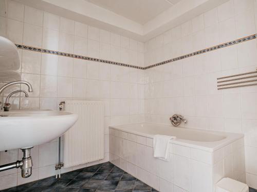 a white bathroom with a sink and a tub at Apartment in Uitgeest by the Waterpark in Uitgeest