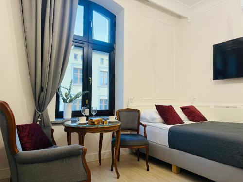 a bedroom with a bed and a table and a window at Apartamenty PREMIUM Rynek 21 in Toruń