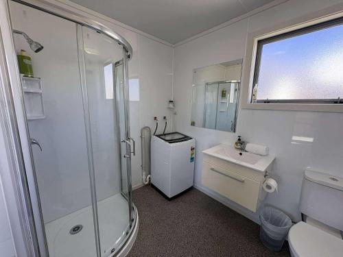 a white bathroom with a shower and a sink at Braeview Cottage in Lake Tekapo