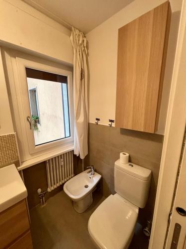 a bathroom with a toilet and a sink and a window at Pragma Apartments - Appartamento Arcade in Predazzo