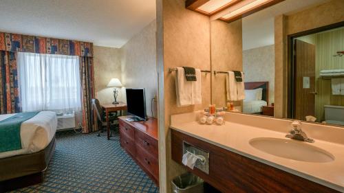 a hotel room with a bathroom with a bed and a sink at Miles City Hotel & Suites in Miles City