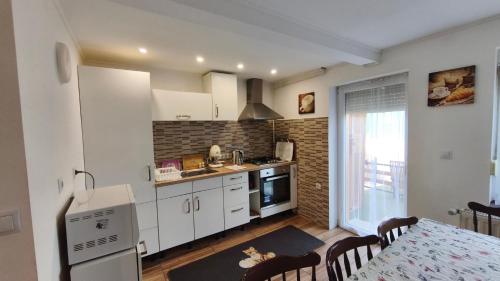 加尔多尼Rigófészek Apartmanház的厨房配有白色橱柜、餐桌和用餐室