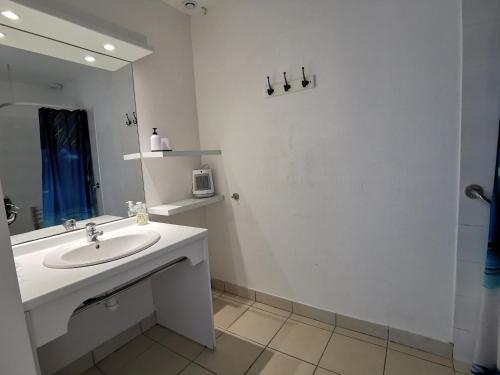 Un baño blanco con lavabo y espejo. en Maison dans résidence mer - piscine, en Loc-Maria-Plouzané