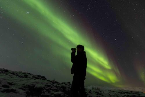 a man taking a picture of the northern lights at Basecamp Dramsvegen Aurora Viewpoint in Tromsø