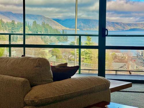 a living room with a couch and a large window at Stunning Lake Views in Queenstown