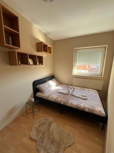 a small bedroom with a bed and a window at River apartman Paraćin in Paraćin