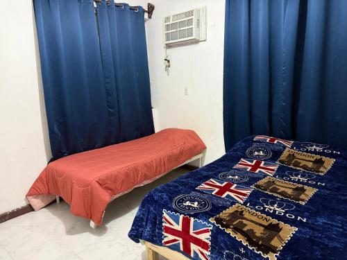 two beds in a room with blue curtains and british flags at Departamento completo bien ubicado in Minatitlán
