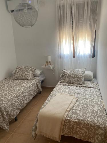 a bedroom with two beds and a window with curtains at Casa rural El Yelmo in Miguel Esteban