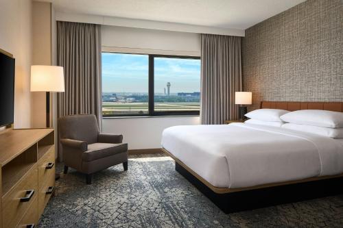 a hotel room with a bed and a chair and a television at Sheraton Suites Chicago O'Hare in Rosemont