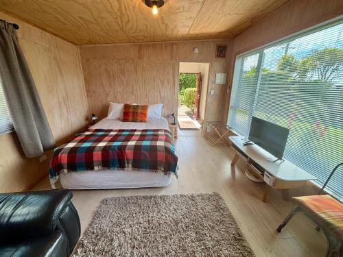 a small room with a bed and a desk and a tv at Brighton Beach in Dunedin