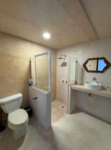 a white bathroom with a toilet and a sink at Departamentos Naa'y in Valladolid