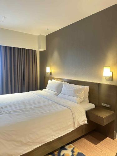 een slaapkamer met een groot bed met witte lakens en kussens bij RBR Lux at Novotel Manila Hotel Residences Acqua in Manilla