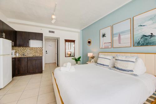 a bedroom with a large white bed and a kitchen at Casablanca Residences Miami Beach in Miami Beach
