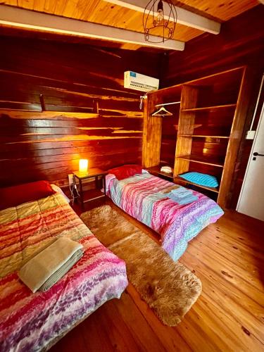 two beds in a room with wooden walls at Cabaña Lomas Del Delta in Esquina