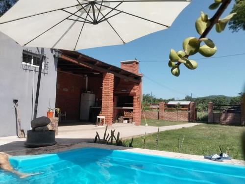 een zwembad met een parasol en een huis bij Quincho Gala in El Cadillal