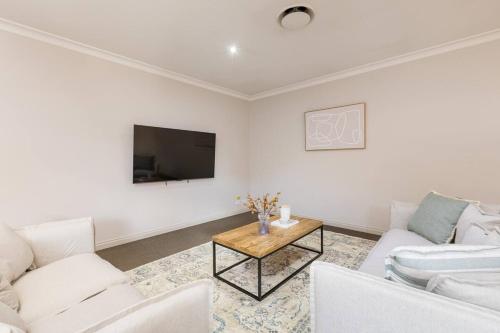 a living room with white furniture and a tv at Mildura City Centre Escape 2 in Mildura