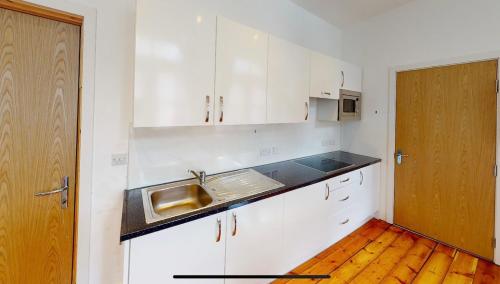 a kitchen with white cabinets and a sink at Modern Studio, Top Floor, King Street Views in Nottingham